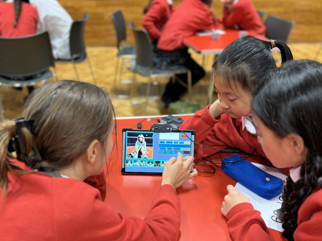 Girl smiling, holding a tablet in a classroom